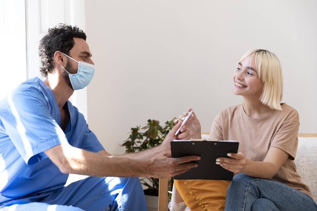 Man sieht einen Mann, der ein Klemmbrett mit Stift von einer Patientin zurückbekommt.